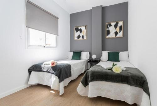 a bedroom with two beds and a window at La La Suites Rianal in Jerez de la Frontera