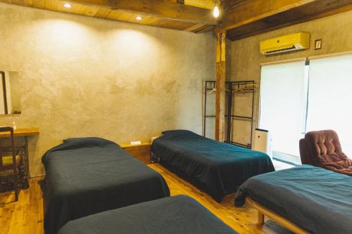 a room with two beds and a table and chairs at Masukichi -hostel,cafe,souvenir,guide- in Seto