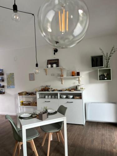 une cuisine avec une table et des chaises blanches et une lampe dans l'établissement Sotto al Bosco B&B e Azienda Agricola, à Dubino