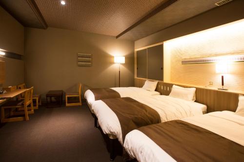 a hotel room with two beds and a table and a desk at Wakkanai Grand Hotel in Wakkanai