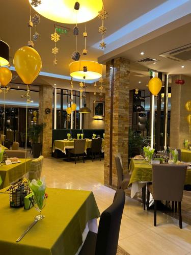 a restaurant with yellow tables and chairs and yellow chandeliers at Family Hotel Ognyanovo in Ognyanovo