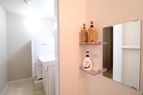 een badkamer met twee flessen aan de muur naast een spiegel bij Tsuruhashi East III in Osaka