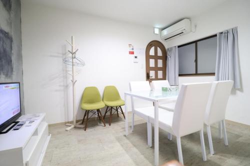 a dining room with a white table and green chairs at Tsuruhashi East III in Osaka