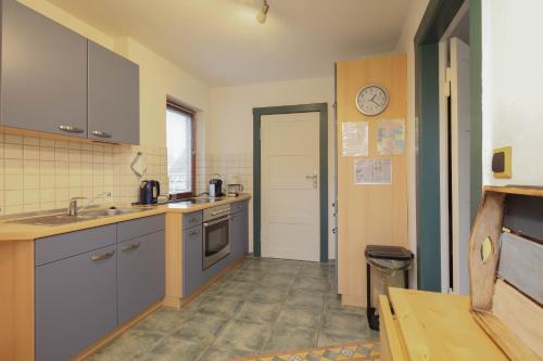 a kitchen with blue cabinets and a clock on the wall at Ferienhaus Seeschwalbe mit großem Garten in Eckernförde