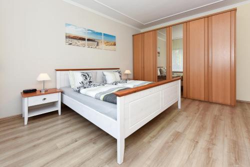 a bedroom with a large white bed and a wooden floor at Ferienwohnungen im Haus Nordseebrise in Neuharlingersiel