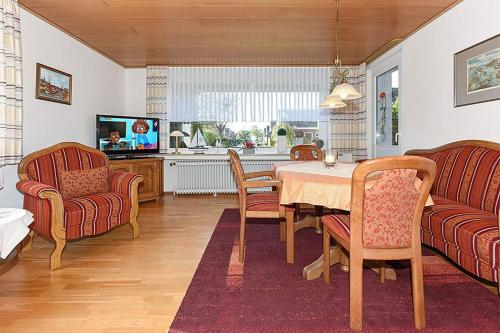 a living room with a table and chairs and a tv at Ferienwohnungen im Haus Nordseebrise in Neuharlingersiel