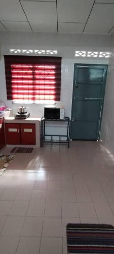 a kitchen with a green door and a white floor at NASP LEGACY GUEST HOUSE in Jasin