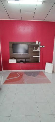 a red wall with a television in a room at NASP LEGACY GUEST HOUSE in Jasin