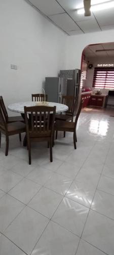 einen Tisch und Stühle in einem Zimmer mit weißem Boden in der Unterkunft NASP LEGACY GUEST HOUSE in Jasin