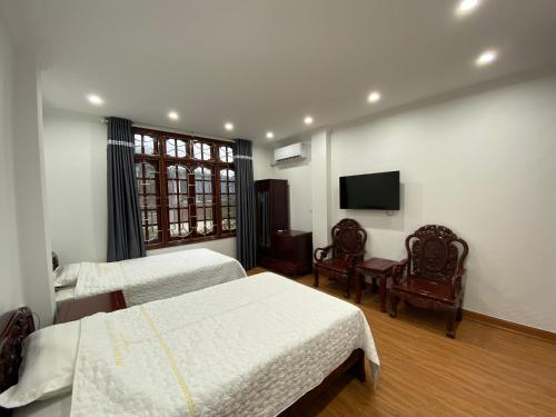 una camera d'albergo con due letti e una televisione di Hương Long Hotel a Móng Cái