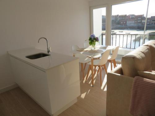 a kitchen with a sink and a table with chairs at Apartamento Centinela Do Mar in O Pindo