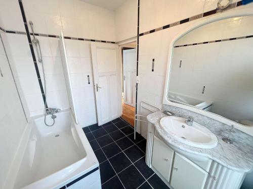 y baño con lavabo, bañera y espejo. en Maison Jullouville, 4 pièces, 6 personnes - FR-1-361-113, en Jullouville-les-Pins