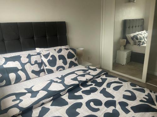 a bedroom with a bed with a black and white comforter and a mirror at 231 Senwick drive in Wellingborough