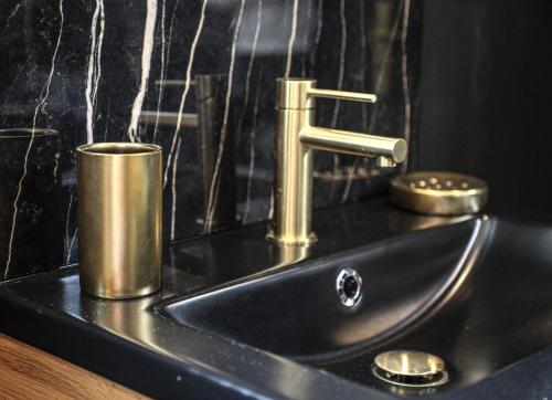 un évier avec un robinet sur un comptoir noir dans l'établissement Le Premium - Suite Spa Privatif, à Pontavert