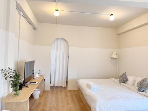 a bedroom with a bed and a desk with a television at La Moon House in Salaya