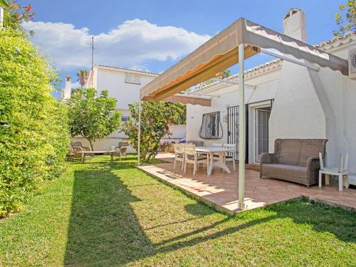 a backyard with a wooden pergola and a table and chairs at Superb beachfront villa with guest house 50m opposite in Mijas Costa