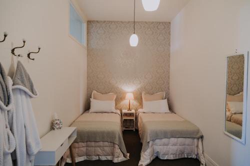 een kleine kamer met 2 bedden en een lamp bij Postmasters Apartment Motueka in Motueka