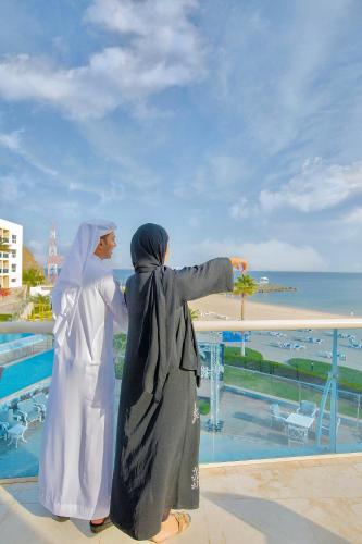two women standing next to each other looking at the ocean at Radisson Blu Resort, Fujairah in Dibba