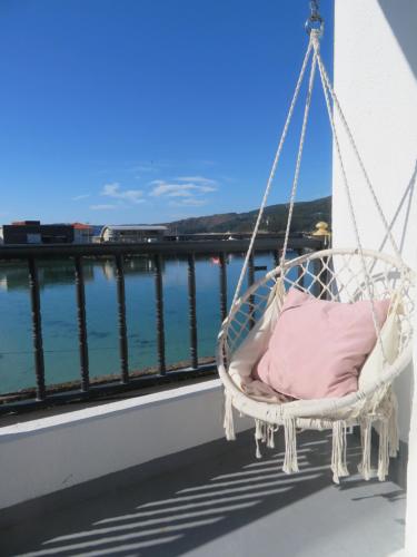 a hanging chair on a balcony overlooking the water at Apartamento Centinela Do Mar in O Pindo