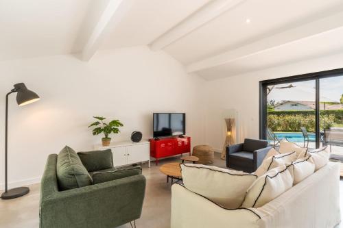 a living room with two couches and a tv at Villa Stendhal - Welkeys in Seignosse