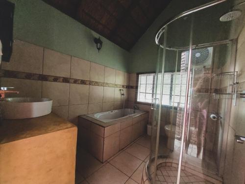un bagno con doccia, lavandino e vasca di HUIS ASEM a Marloth Park