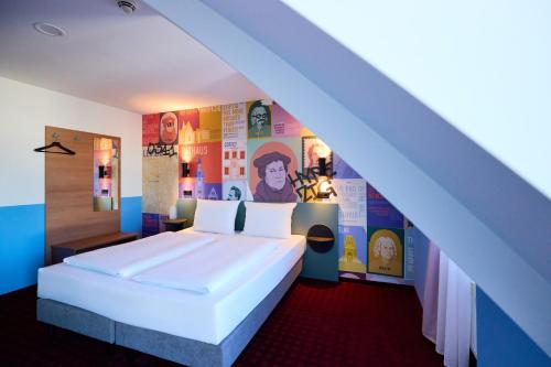 a bedroom with a large white bed and colorful walls at McDreams Hotel Leipzig in Leipzig
