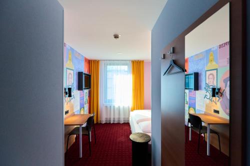 una camera d'albergo con un letto e due scrivanie e un letto e una camera di McDreams Hotel Leipzig a Lipsia