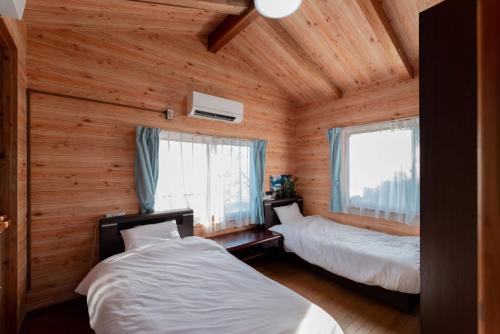 two beds in a room with wooden walls and windows at VIVA SUMOTO - Vacation STAY 81374v in Amakusa