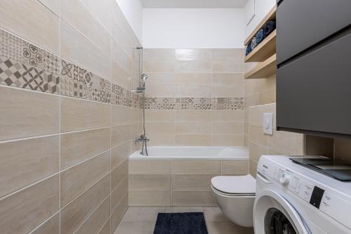 a bathroom with a toilet and a tub and a washing machine at Bay Shore Flat in Budapest