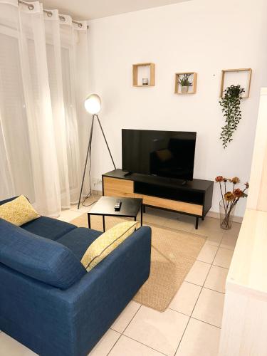 a living room with a blue couch and a tv at « Le Cosy » Cergy le Haut RER A in Cergy