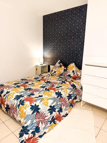 a bedroom with a bed with a floral bedspread at « Le Cosy » Cergy le Haut RER A in Cergy