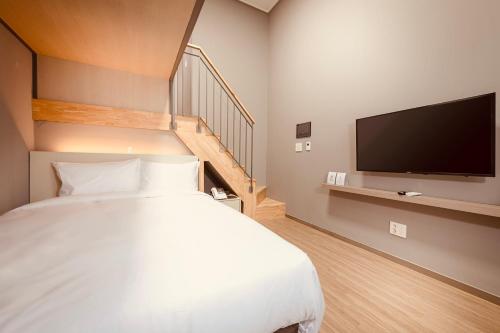 a bedroom with a bed and a tv and a staircase at Sollago Myeongdong Hotel & Residence in Seoul