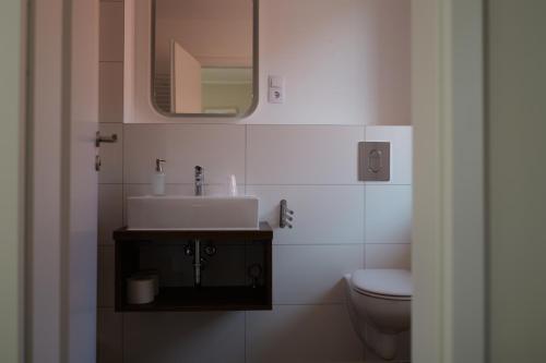 uma casa de banho com um lavatório, um WC e um espelho. em Hotel Milano em Hildesheim
