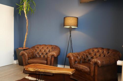 two leather chairs and a lamp in a living room at Hotel Milano in Hildesheim
