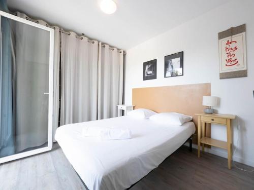 1 dormitorio con cama blanca y ventana en Confortable, lumineux et agréable T3, en Montpellier