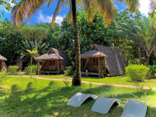 a group of cottages with chairs in the grass at Aurora Lodge in Ile aux Nattes