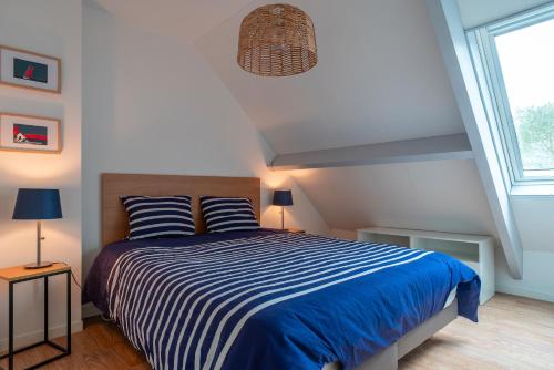 - une chambre avec un lit bleu et blanc et une fenêtre dans l'établissement La Terrasse du Golf - Appt avec terrasse, à Bénodet