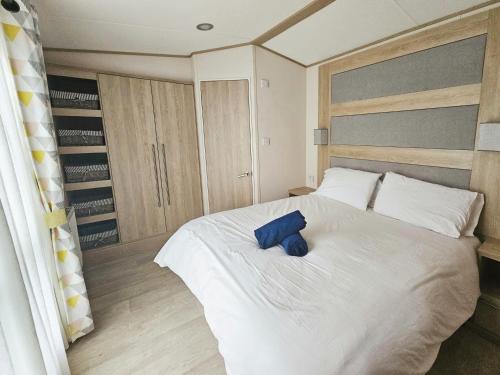 ein Schlafzimmer mit einem weißen Bett und einem blauen Kissen darauf in der Unterkunft Hot Tub Lodge in the Cotswolds - Pet Friendly in South Cerney