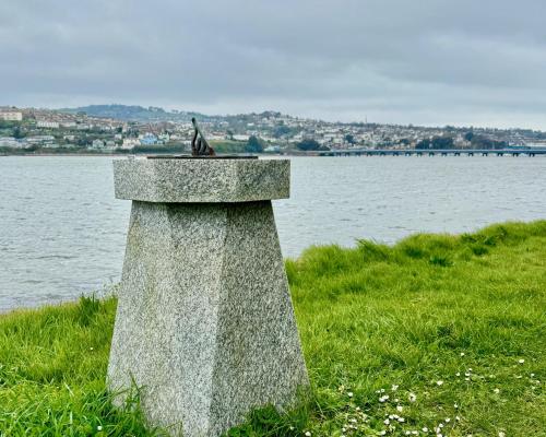 a bird sitting on top of a stone tower next to the water at Historic 'Old Toll House' Shaldon Bridge in Teignmouth