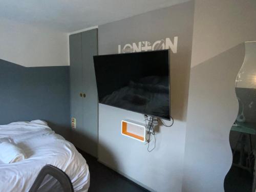 a room with a flat screen tv on a wall at Luxurious En-suite Soft Water Air Conditioning TV ETHERIUM in London