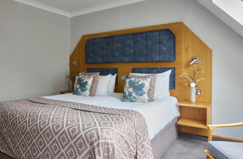 a bedroom with a large bed with a wooden headboard at Fairlawns, Hotel And Spa in Walsall