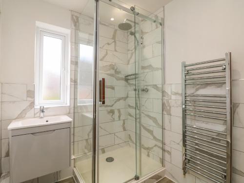 uma casa de banho com uma cabina de duche em vidro e um lavatório. em Riversdale Cottage em Wadebridge