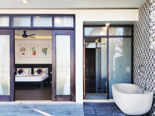 una camera con porte in vetro, una sedia e un letto di Starlight Villa Beach Resort a Phan Thiet