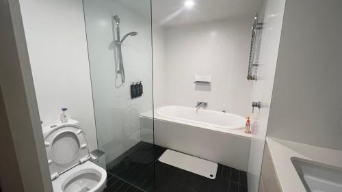Baño blanco con aseo y lavamanos en 2 Bedroom Apartment Eco Living at Nishi Canberra, en Canberra