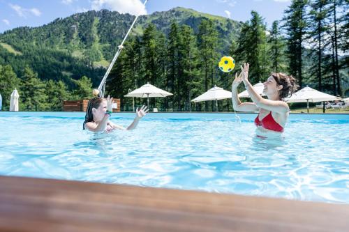 duas mulheres a brincar com uma bola numa piscina em Villages Clubs du Soleil - MONTGENEVRE em Montgenèvre
