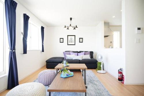 a living room with a couch and a table at 【エメラルド色の海が目の前に！】自然を満喫できるロケーション。お洒落な感じの4LDK一軒家貸し切り！ in Yaka