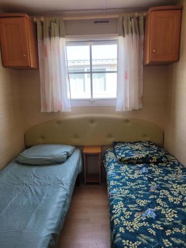une petite chambre avec deux lits et une fenêtre dans l'établissement Mobile home à 200m de la mer dans camping familial avec piscine, jeux et activités, à Pornic