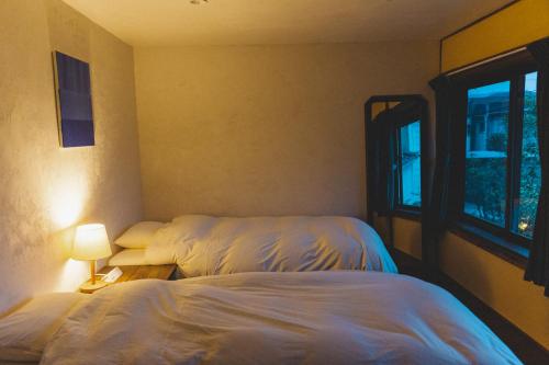 a bedroom with two beds and a window at Masukichi 古民家宿ますきち 駐車場無料 in Seto