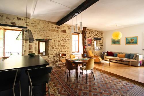eine Küche und ein Wohnzimmer mit einem Tisch und Stühlen in der Unterkunft Ancienne maison en pierre au coeur du village in Usclas-lʼHérault