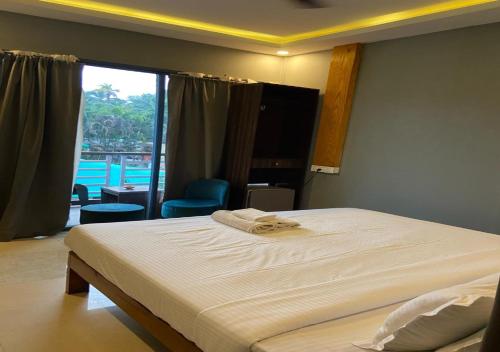 sypialnia z łóżkiem i dużym oknem w obiekcie Yogitree Beach Resort & Cafe w mieście Morjim